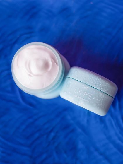 A top-down shot of the DHC moisturizer on a rich blue, furry texture. The contrast in color and texture makes the light blue product container pop.
