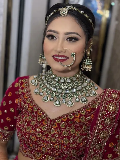 A portrait of the bride looking directly at the camera. Her eyes are the centerpiece of the look, with sharp liner and shimmering shadow, paired with a confident red lipstick.