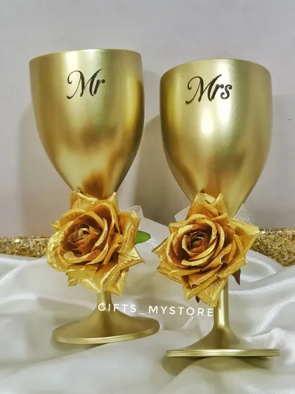 A pair of custom "Mr." and "Mrs." golden wine glasses, a perfect addition to any wedding or anniversary hamper.