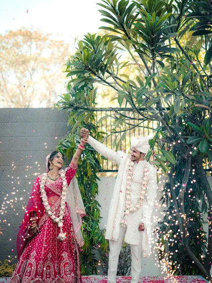A moment of pure triumph and joy after the varmala ceremony, with the couple raising their hands in celebration amidst sparklers.