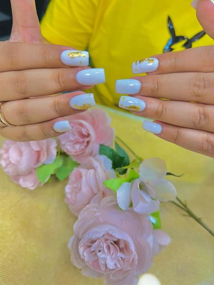 A soft, light blue set of nails with delicate gold foil accents. The square shape and pastel color make this a lovely, understated design.