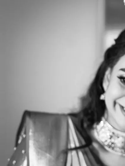 A joyful, candid smile from the bride, Kavya, captured in a beautifully composed black and white frame.