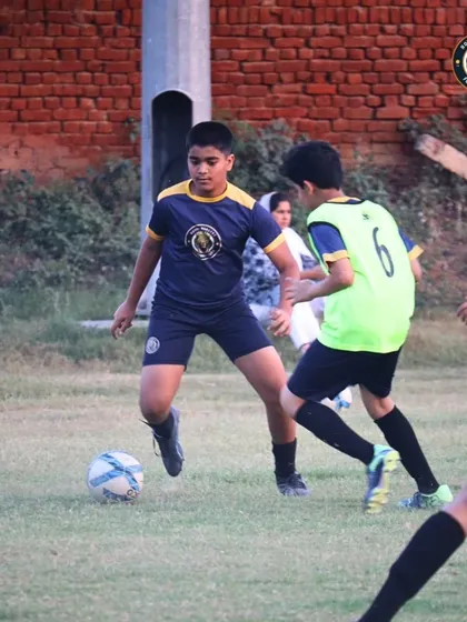A player shields the ball from a defender during a practice drill. Learning to protect the ball under pressure is a crucial skill for maintaining possession and controlling the game.