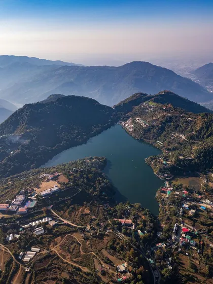 A wide aerial photograph of Naukuchiatal, capturing the lake nestled within the Himalayan foothills of Uttarakhand. This shot showcases my landscape photography service, perfect for highlighting the natural beauty of travel destinations or real estate properties from a breathtaking perspective.