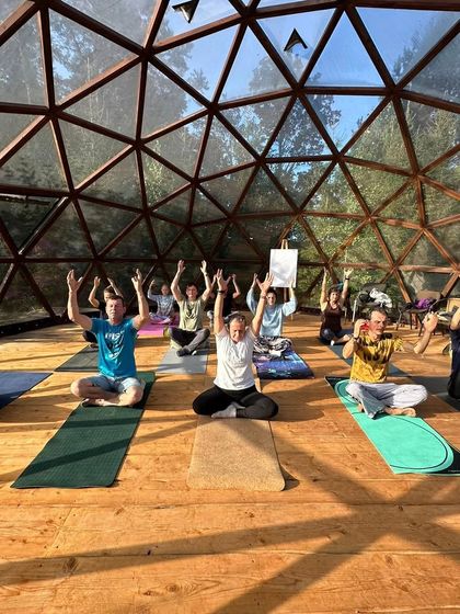 Students are seen here in a seated posture with arms raised, a preparatory pose that helps to lengthen the spine and open the shoulders. This was taken during a morning session focused on creating energy for the day ahead.