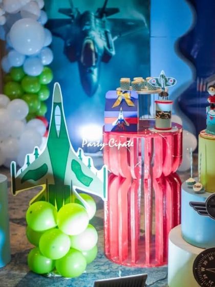 The dessert table for the fighter jet party, featuring the cake and other themed treats displayed on colorful plinths.
