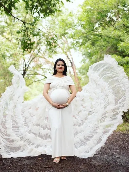 This shot showcases the "flying wings" effect of our white ruffled gown. It's a stunning way to add a touch of magic and drama to your maternity photos.
