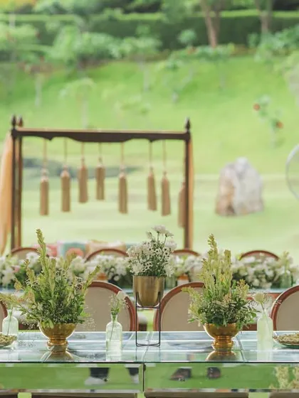 A long view of the guest dining setup, with clean lines, mirrored tables, and elegant floral arrangements, set against a beautiful natural backdrop.