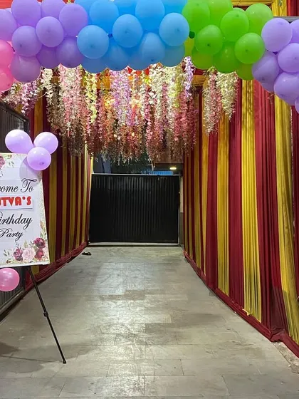 A colorful entrance for a Masha and the Bear themed party, with a rainbow balloon arch and a custom welcome sign.