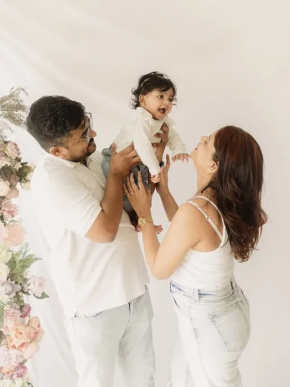 The pure joy of family. A father lifts his laughing baby girl while her mother looks on with love. These are the playful, energetic moments I aim to freeze in time.