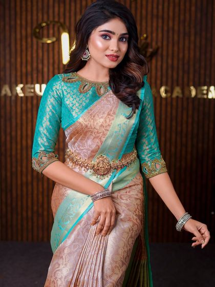 This model is wearing a unique beige and teal saree. The drape is styled to highlight the unusual color combination and the intricate blouse neckline.