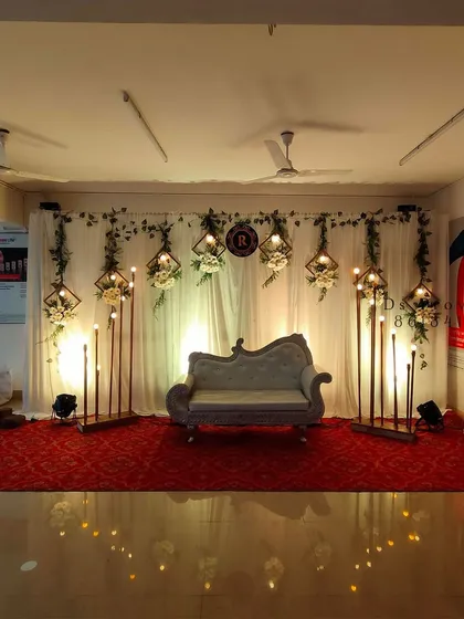 This is a great example of a modern and elegant stage for a reception or engagement. I used a clean white backdrop with hanging geometric frames, floral accents, and unique standing lights to create a sophisticated atmosphere.