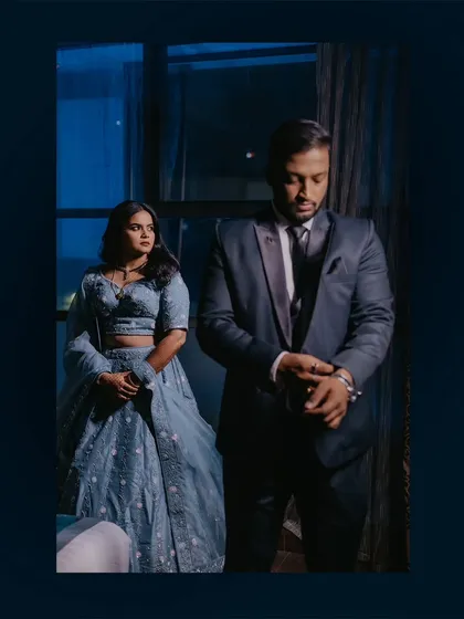 A moody, cinematic portrait of the couple by a window at night, capturing a quiet, in-between moment.