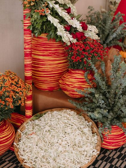 Baskets of fresh white petals and colorful striped vases add texture and vibrancy to the Ganesh Pooja decor, showing our attention to detail in every ceremony.