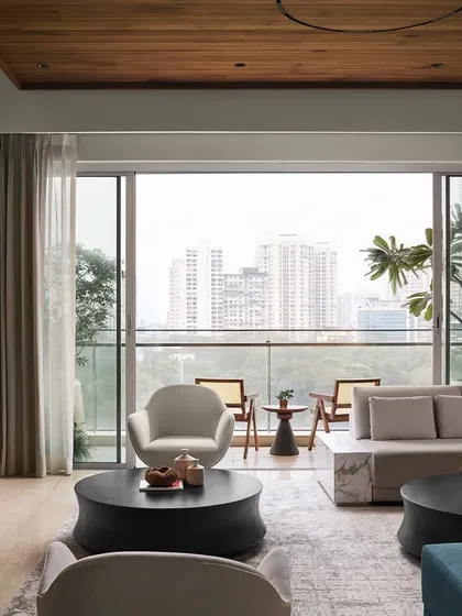 The living room of Lumen House is designed to be an urban retreat, where a warm neutral palette and a natural wood ceiling create a foundation of comfort. The space opens onto an expansive balcony, blurring the lines between indoors and out and flooding the room with natural light.