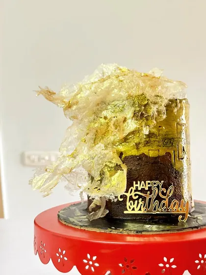 A truly decadent cake. This is a Belgian Chocolate and dark toffee cake, decorated with abstract gold leaf and a dramatic, textured wafer paper sail.
