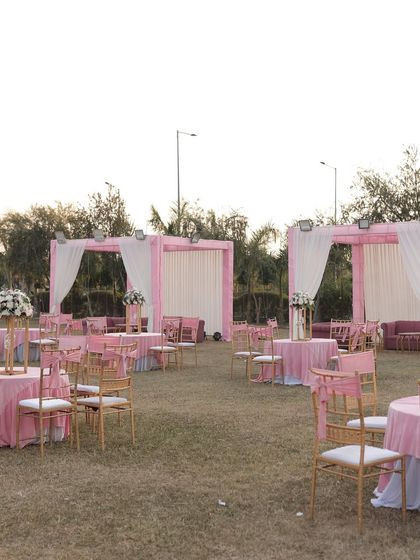 A wide view of the outdoor lawn setup, with pink and white themed guest tables and cabanas, creating a cohesive and beautiful event space.
