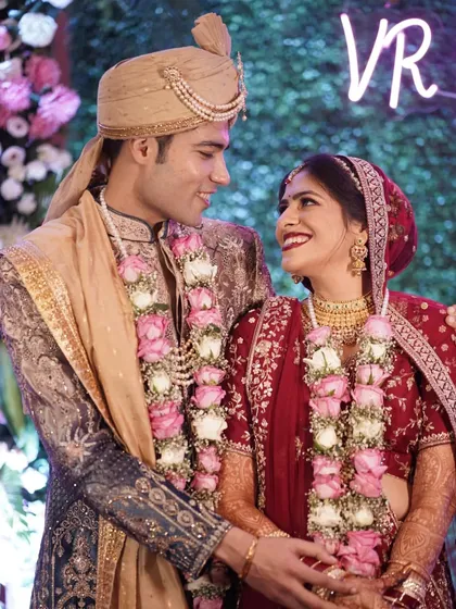 The couple shares a romantic glance in front of a neon sign, a modern touch to their wedding celebration.