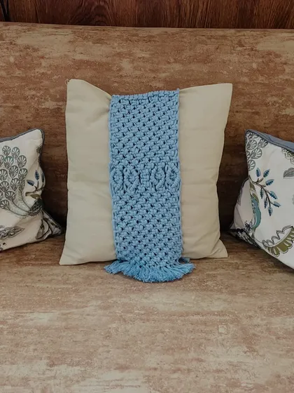 This view shows the blue tie-back on a sofa, nestled between other pillows. The detailed knotting stands out and adds a layer of visual interest to your living room decor.