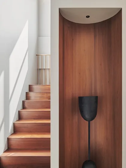 This image showcases the elegant combination of wood and light in the Maximum City Residence staircase. A recessed niche lined with wood creates a focal point for a decorative object, turning the stairwell into a curated space.