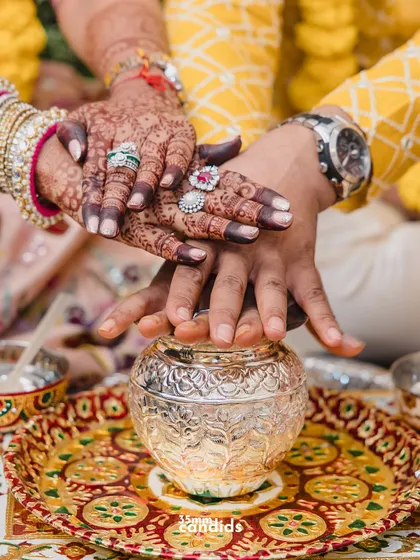 A close-up of the couple's hands during a wedding ritual. This shot highlights the beautiful henna, the rings, and the symbolism of their union.