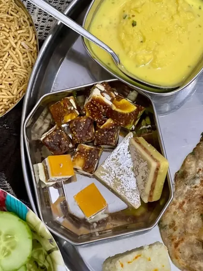 A complete meal platter from one of my catering events. It includes a variety of breads, curries, sweets like Rasmalai and Kalakand, and salad, offering a full dining experience.