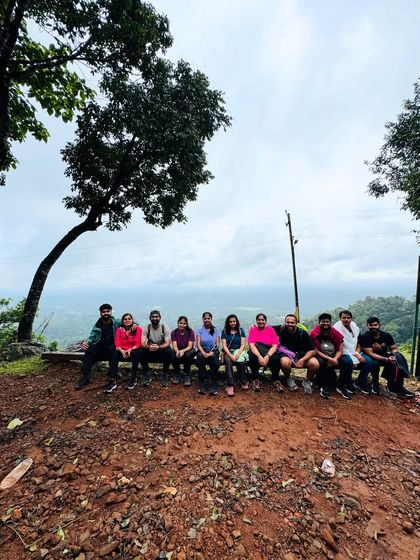 The team resting on a bench with a panoramic view of the Coorg valley.