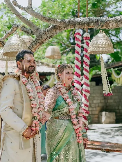 A cross-cultural couple stands together near the floral swing, showcasing how our venue welcomes and celebrates love stories from all backgrounds.