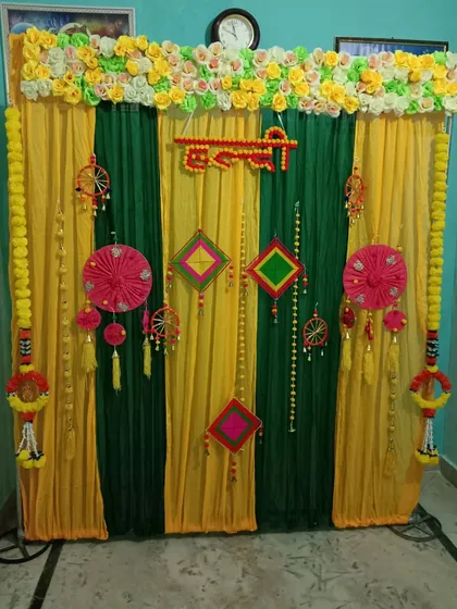 I offer traditional decoration services for pre-wedding functions like the Haldi ceremony. This backdrop uses vibrant yellow and green drapes, marigold flower garlands, and traditional Indian hangings to create an authentic and festive atmosphere for your event.