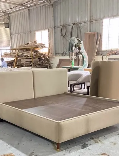 Minimalist chic meets maximum comfort. A custom-made bed with a simple, clean-lined upholstered frame and headboard, seen here in our factory before being shipped.