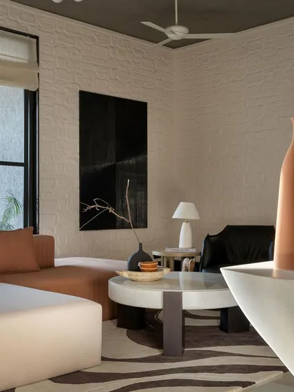 Another view of a living room with a textured wall and a dark, moody painting. The space balances neutral tones with organic elements, with custom furniture crafted for comfort and style.