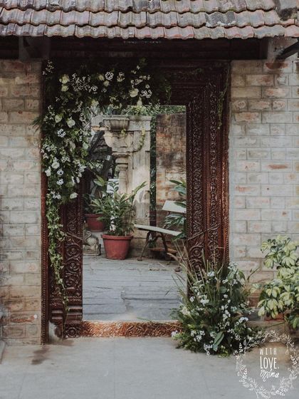 An antique doorway at the wedding venue, framed with an asymmetrical arrangement of white flowers and greenery.
