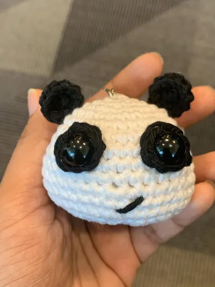 A closer look at the panda head charm, showing the detailed stitching and cute embroidered smile.