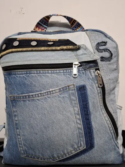Each upcycled denim backpack I make is one-of-a-kind. This one features an initial 'S' and uses different parts of the original jeans, including the waistband and pockets, for a truly unique design.