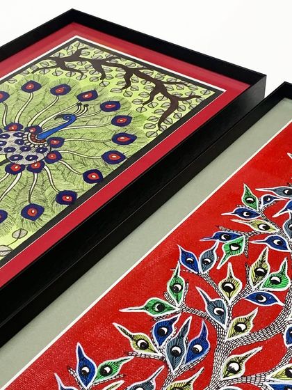 A detailed look at the layers of framing for these peacock artworks, showing the black metal frame, the red inner mat, and the gray outer mat working together to create depth.