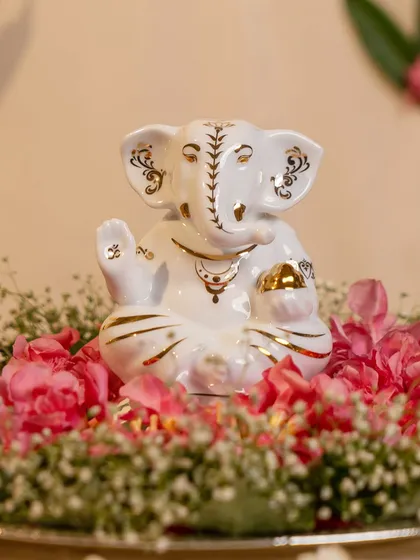 This elegant white porcelain Ganesha, with delicate gold accents, brings a sense of pure divinity and peace. Surrounded by flowers, it is a serene and beautiful representation of the beloved deity.
