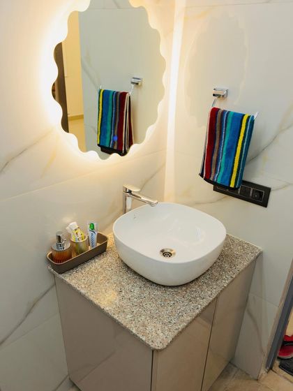 A close-up of the vanity area with a beautiful wavy backlit mirror and a clean, minimalist countertop.