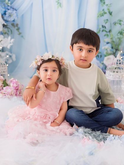 A classic sibling portrait. The big brother puts a protective arm around his little sister in this beautifully styled floral wonderland setup.