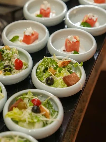 Individual portions of Caesar salad and watermelon feta salad, beautifully presented and ready for guests to enjoy.
