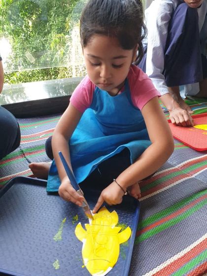 A young girl carefully painting a star-shaped cutout. Our space-themed art activities include making planets, rockets, and constellations.