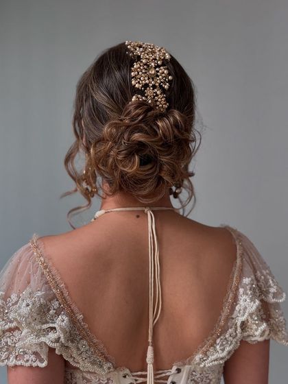 A soft, romantic updo with a beautiful gold accessory, perfect for a Christian bride or a reception.