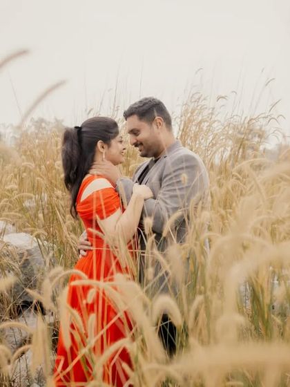 A romantic shot of a couple embracing amidst tall grass, with the blades creating a soft frame around them.