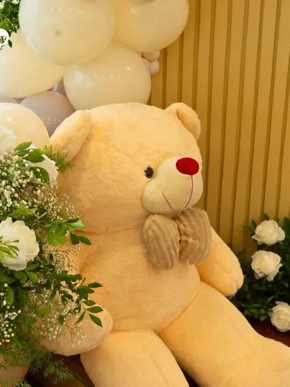 A close-up of the adorable teddy bear detail, surrounded by fresh white roses. It's these small, thoughtful touches that bring a theme to life and make a celebration feel special.