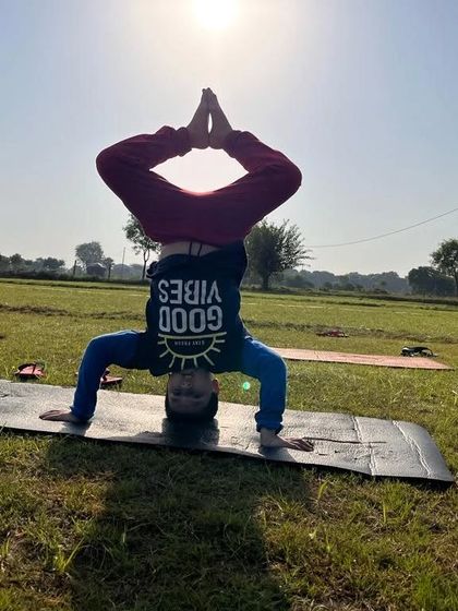 A student holding a headstand against the morning sun. Practicing inversions outdoors can feel incredibly empowering.