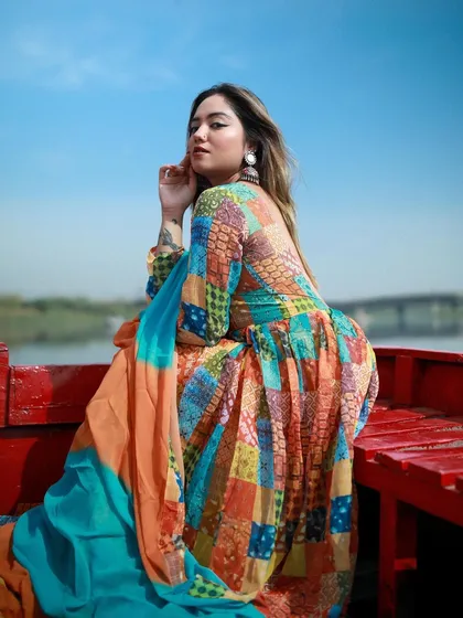 An outdoor editorial shot of a model in a colorful patchwork dress on a boat at Yamuna Ghat. This photo showcases my ability to use natural light and unique locations to tell a compelling story.