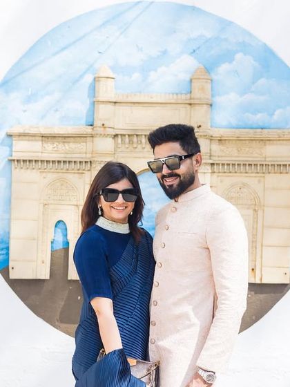 A stylish couple portrait in front of a mural of the Gateway of India. This is a great way to include an iconic landmark in your photos with a creative twist.