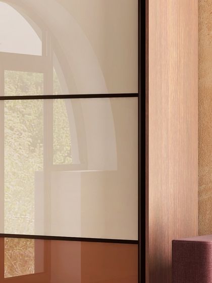 This image shows a sliding wardrobe door with translucent panels next to a seating area, demonstrating how our designs can complement the overall room architecture.
