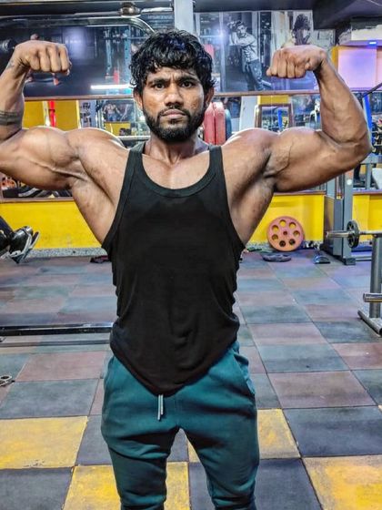 A front double bicep pose, a classic bodybuilding stance. This is the result of years of learning and applying the right techniques, something I teach all my clients.