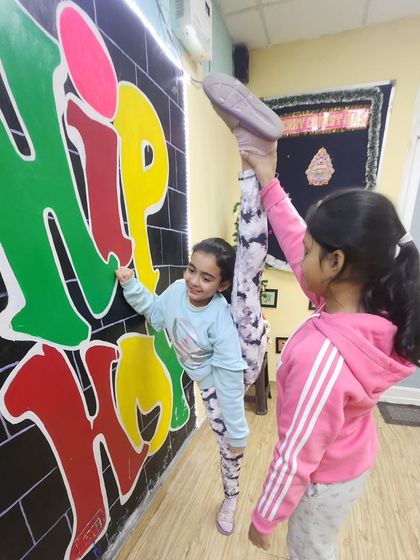 Stretching can be fun too. Our young dancers help each other with leg holds and kicks, building both flexibility and teamwork in the process.