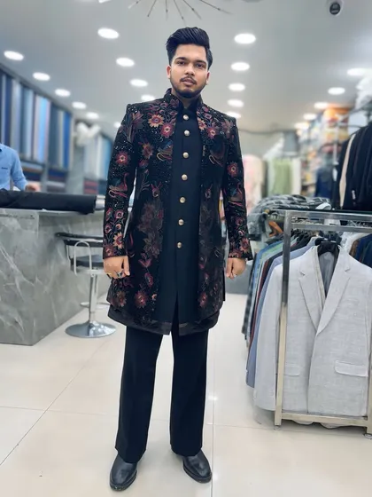 The designer modeling a black Indo-Western sherwani with vibrant floral embroidery. This piece is perfect for making a statement at any festive occasion.